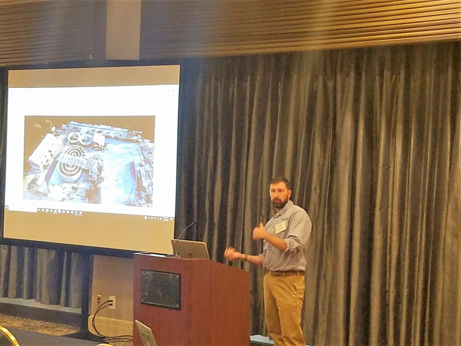 Instructor presenting to a conference session with slides on screen